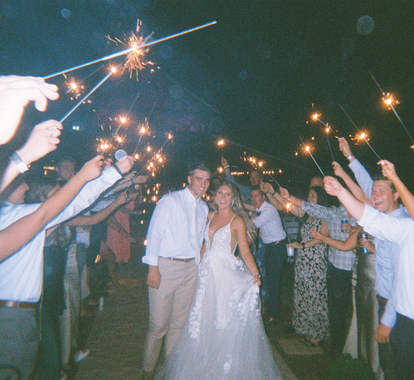 Wedding sparkling send off with sparklers in air as bride and groom walk