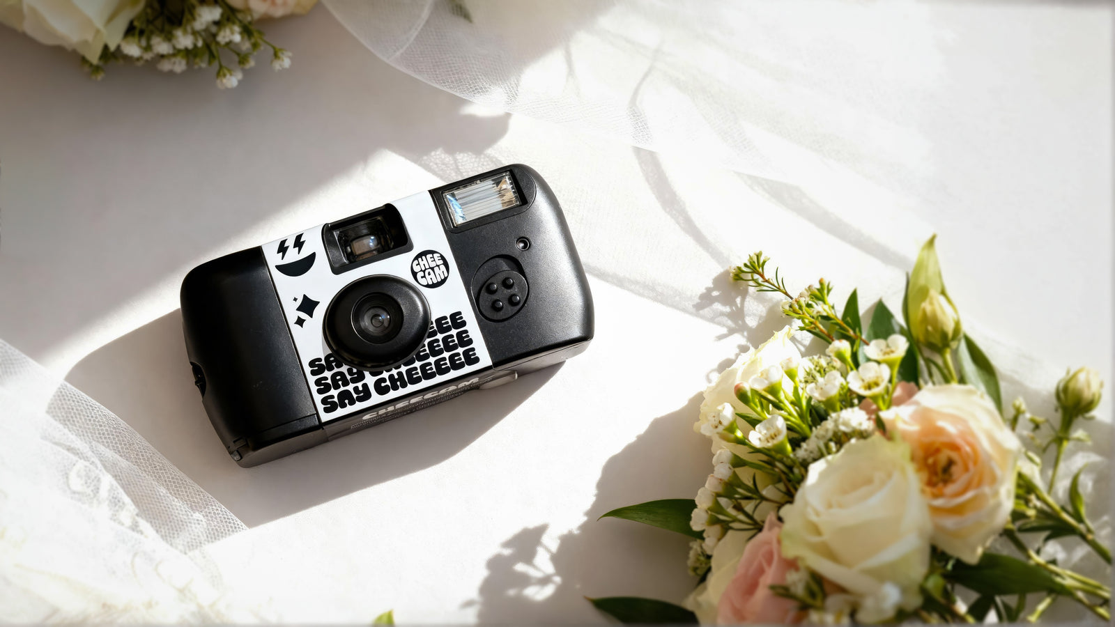 The Cheecam single-use wedding camera, hand-loaded with Kodak film, styled on linen with roses